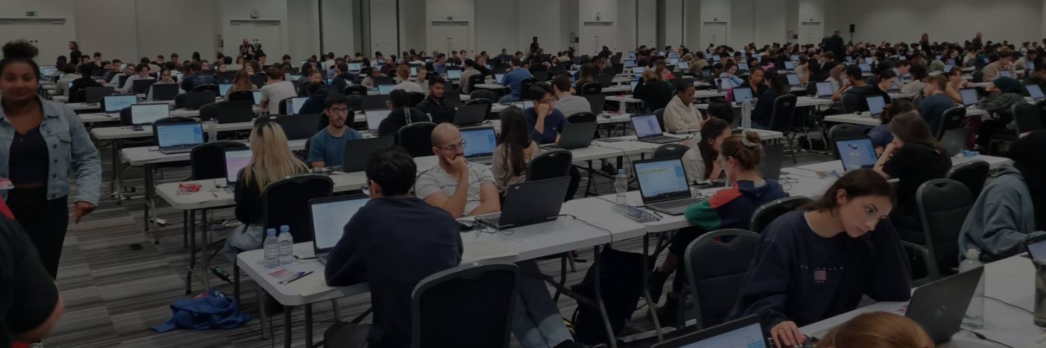 Large examination hall filled with rows of desks, each equipped with a laptop for digital testing.