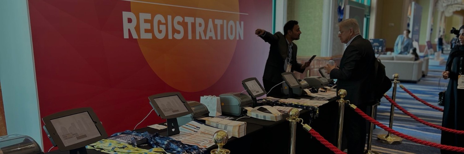 Event registration counter featuring touchscreen tablets, badge printers, and organized attendee materials.