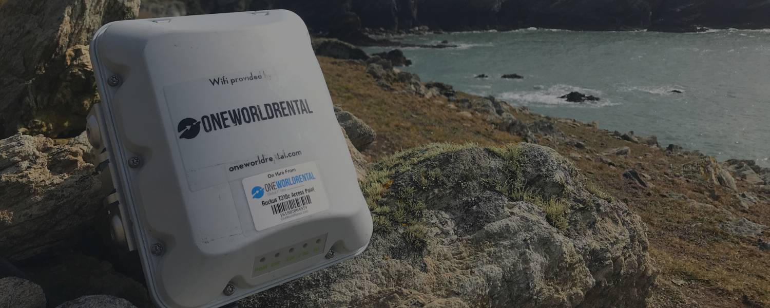 Portable Wi‑Fi access point from One World Rental positioned on a coastal landscape.